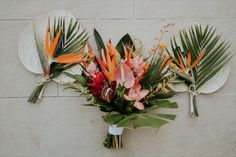 an arrangement of tropical flowers and leaves on a wall