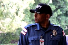 a police officer is standing in front of some trees and looking off into the distance