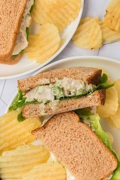 two plates with sandwiches and potato chips on them, one has lettuce and the other has chicken salad