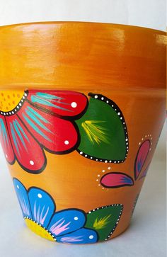 an orange flower pot with colorful flowers painted on it