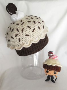 a knitted cupcake hat next to a crochet doll on a white background