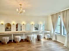 a large room with mirrors, stools and lights on the wall in front of windows