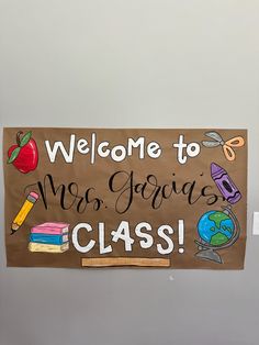 a welcome sign hanging from the side of a wall with writing on it and school supplies