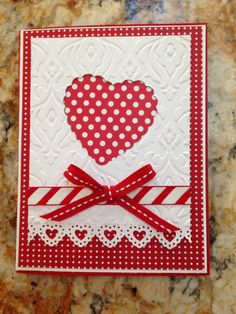 a red and white card with a heart on the front, ribbon around the edge