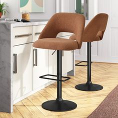 two yellow chairs sitting on top of a wooden floor next to a kitchen counter with a potted plant