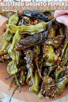 a plate filled with cooked green peppers on top of a wooden cutting board