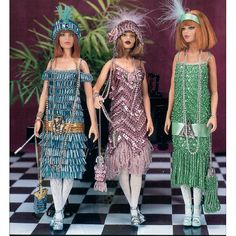 three barbie dolls dressed in flappy outfits and headdress, standing on a checkered floor