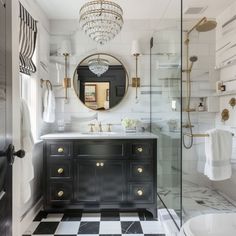 a bathroom with black and white checkered flooring, chandelier above the sink