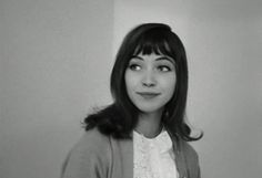 a black and white photo of a woman with long dark hair wearing a cardigan