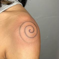 a woman's shoulder with a tattoo on the back of her arm and an abstract spiral design