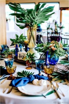 the table is set with blue and white plates, silverware, and greenery