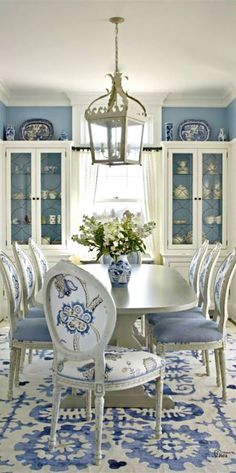 a dining room table with blue and white china on the wall behind it, surrounded by chairs