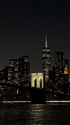 the city skyline is lit up at night as seen from across the water in new york