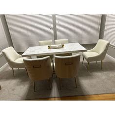 a dining room table with four chairs and a white marble top in front of blinds