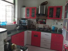 a kitchen with red and white cupboards, black counter tops, and a window