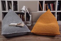 two knitted bean bags sitting on top of a wooden floor next to a book shelf