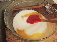 a glass bowl filled with yogurt and sauce on top of a wooden cutting board