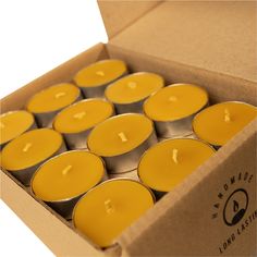 twelve yellow candles in a cardboard box with the lid open to show their wax inside