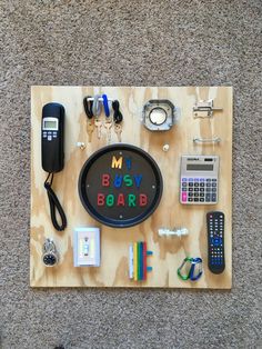 a wooden board topped with assorted items on top of carpeted floor next to wall