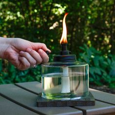 a person holding the hand of another persons hand over a lit candle on a table