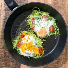 two eggs and vegetables in a pan on a wooden table