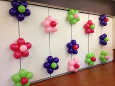 there are many balloons attached to the wall with flowers on each one and in different colors