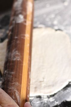 a person holding a piece of wood in front of a doughnut on a table