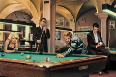 three men and two women are playing pool