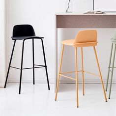 three different colored stools in front of a desk