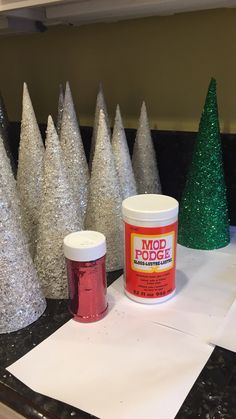 some glittered trees are sitting on a table next to paint and paper towels with the words wood lodge written on them