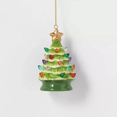 a green glass christmas tree ornament hanging from a gold chain