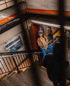 people are walking up and down the stairs in an underground subway station, with one person wearing a blue hat