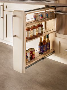 an open cabinet in the middle of a kitchen with lots of spices and condiments