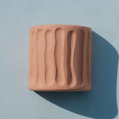 a clay vase sitting on top of a blue wall