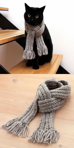 a black cat sitting on top of a wooden table next to a gray and white scarf