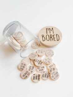 i'm bored wooden tokens in a glass jar next to a bottle filled with coins