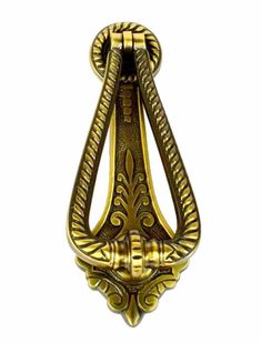 a gold colored metal hook with ornate designs on the front and back ends, attached to a white background