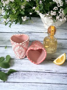 three small vases sitting next to each other on a wooden table with flowers in the background