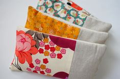 four different colored flowered fabric bags sitting next to each other on a white surface