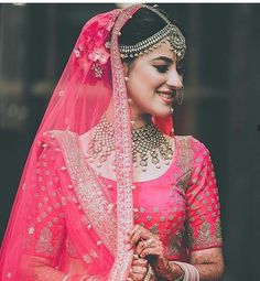 a woman wearing a pink and gold bridal outfit with her hands on her hip