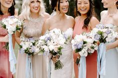 a group of women standing next to each other holding bouquets and smiling at the camera