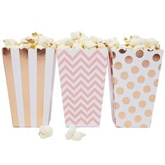 three pink and gold striped popcorn boxes with polka dots on the top, one is filled with popcorn