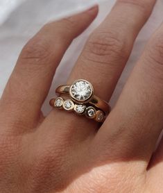 a woman's hand with two gold rings on it and one diamond in the middle