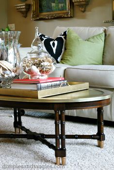 a coffee table with books and vases on it in front of a white couch