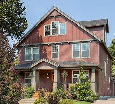 a red house with lots of windows on the front and side of it, surrounded by greenery