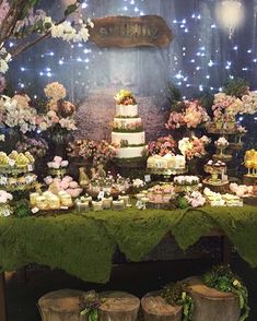 a table topped with lots of cakes and desserts next to a wall covered in lights