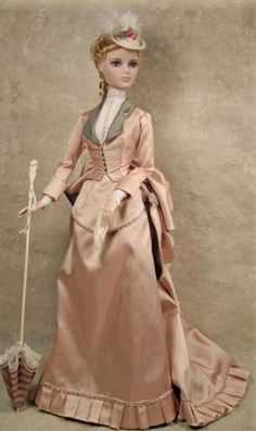 a doll is dressed in pink and holding a cane while standing next to a wall