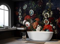 a bath tub sitting in front of a window next to a wall with flowers on it