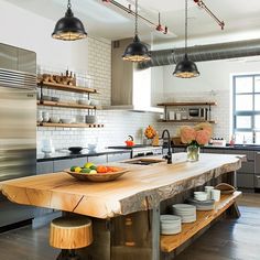 a large kitchen island in the middle of a room with lots of counter space and hanging lights