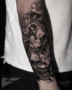 a black and white photo of a person with a tattoo on his arm that has flowers growing out of it
